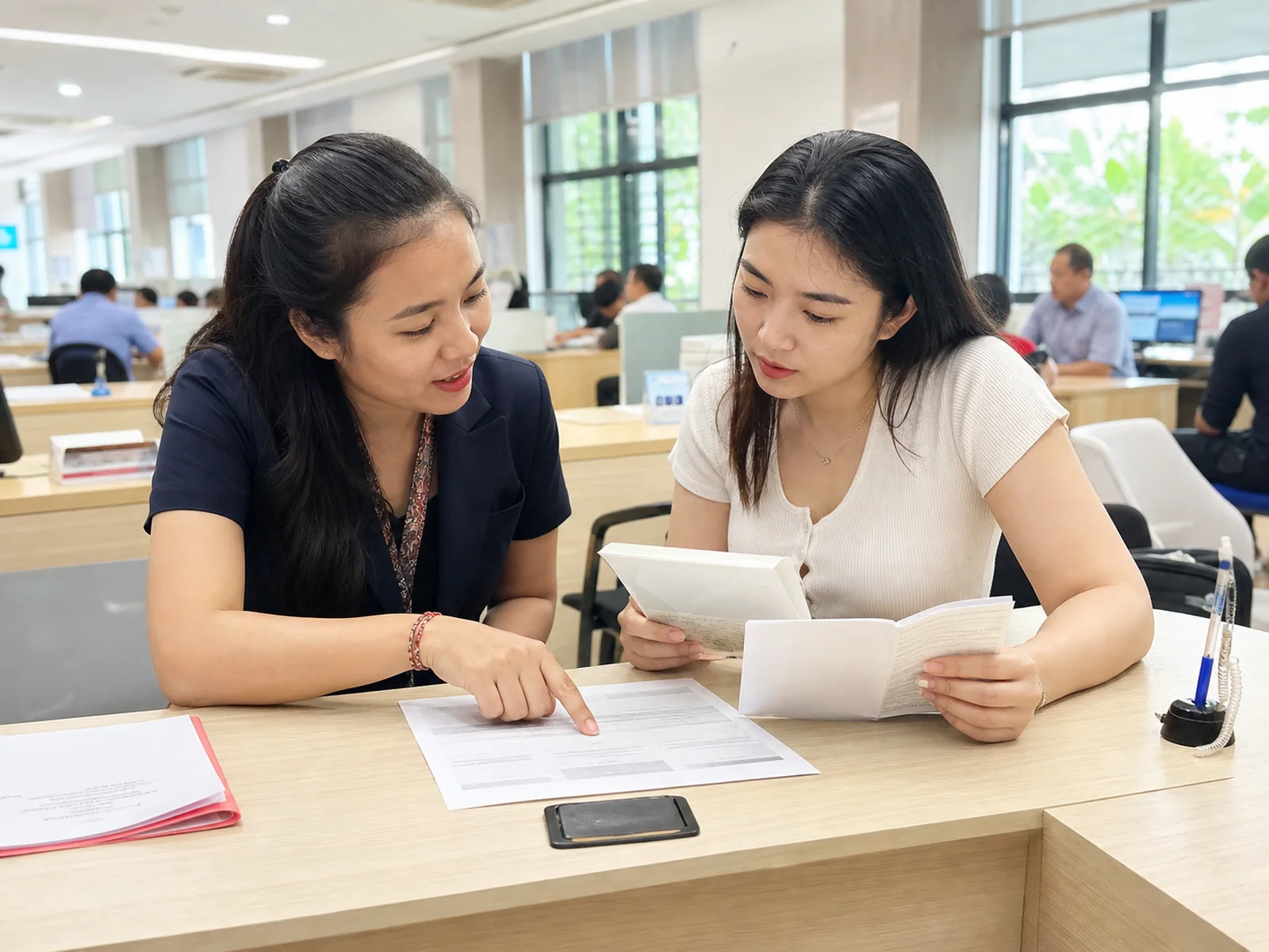 Staff member explaining service criteria to a resident at an assistance desk.
